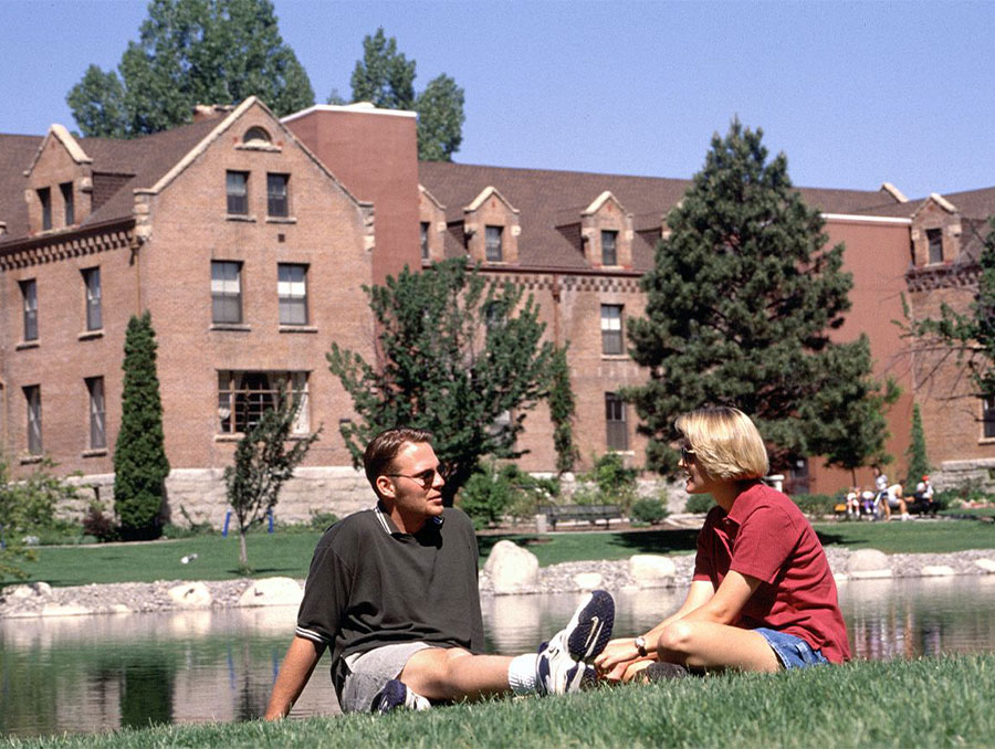 Two students shit close together talking in front of Manzanita Hall and Manzanita Lake, 2000